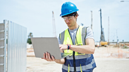 Young hispanic man architect using laptop working at construction place