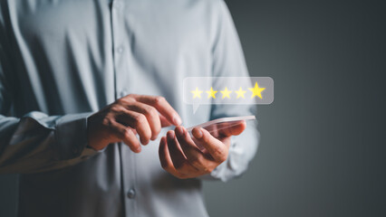 Close up on customer hand pressing on smartphone with gold five-star rating feedback icon and press level excellent rank for giving best score point to review the product and service, business concept