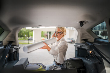 mature blonde woman travel take stuff belongings from the back of car