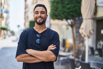 Young arab man standing with arms crossed gesture at street
