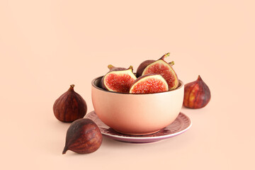 Bowl with fresh juicy cut figs on pale pink background