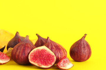 Paper with fresh juicy cut figs on yellow background