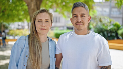 Man and woman couple standing together with serious face at park