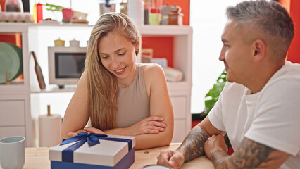 Man and woman couple sitting on table with gift at dinning room