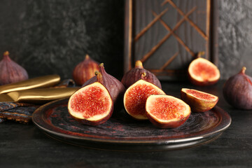 Plate with fresh ripe figs on black background
