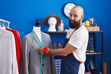 Young bald man tailor smiling confident measuring jacket at clothing factory