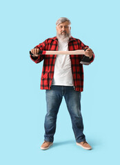 Portrait of mature lumberjack with axe on blue background