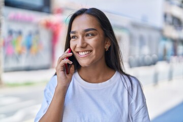 Young beautiful hispanic woman smiling confident talking on the smartphone at street