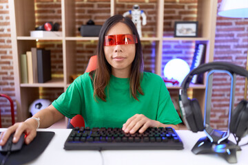 Middle age chinese woman wearing virtual reality glasses smiling looking to the side and staring away thinking.