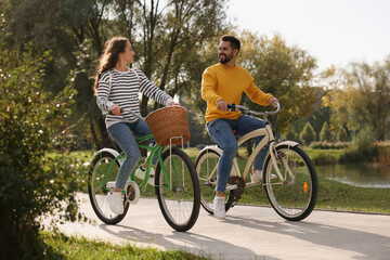 Beautiful young couple riding bicycles in park