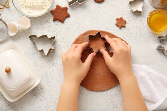 Woman preparing tasty Christmas gingerbread cookies on grunge white background