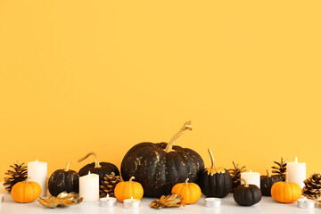 Pumpkins and candles near yellow wall