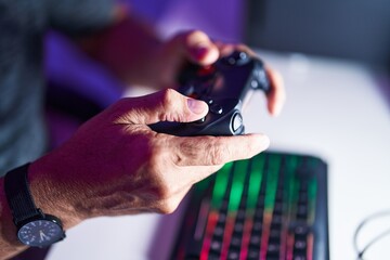 Middle age grey-haired man playing video game using joystick at gaming room