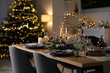 Christmas table setting with festive decor and dishware in room