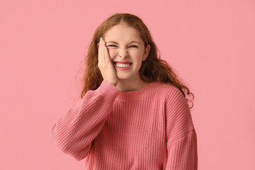 Portrait of nervous young woman smiling on pink background