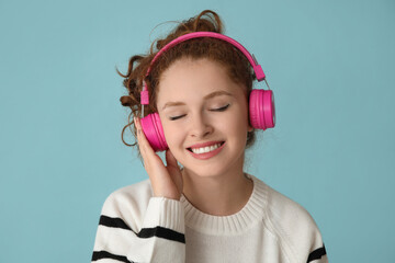 Portrait of relaxed young woman listening to music on blue background
