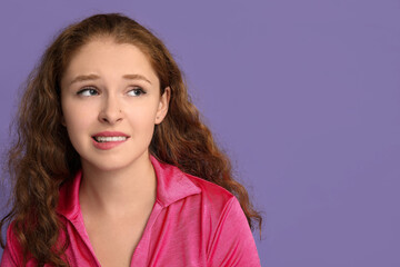 Fototapeta premium Portrait of nervous young woman on purple background