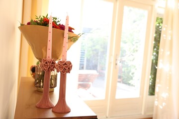 Bouquet of flowers and candles on wooden table indoors. Space for text