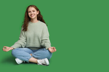 Fototapeta na wymiar Portrait of relaxed young woman meditating on green background