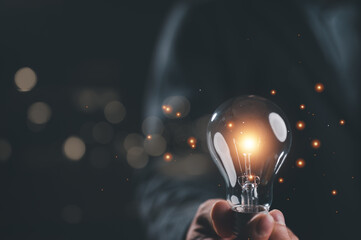 Businessman holding illuminated lightbulb, idea, innovation and inspiration with glowing light,...