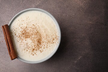 Delicious semolina pudding with cinnamon in bowl on brown table, top view. Space for text