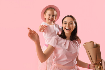 Cute little daughter greeting her beautiful mother with bouquet of roses on pink background. Happy  Mother's Day