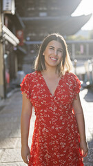 Beautiful hispanic woman smiling joyfully, confidently posing, standing on the old traditional streets of gion, kyoto, her sunny, carefree nature shining through for a fun-filled japan adventure.