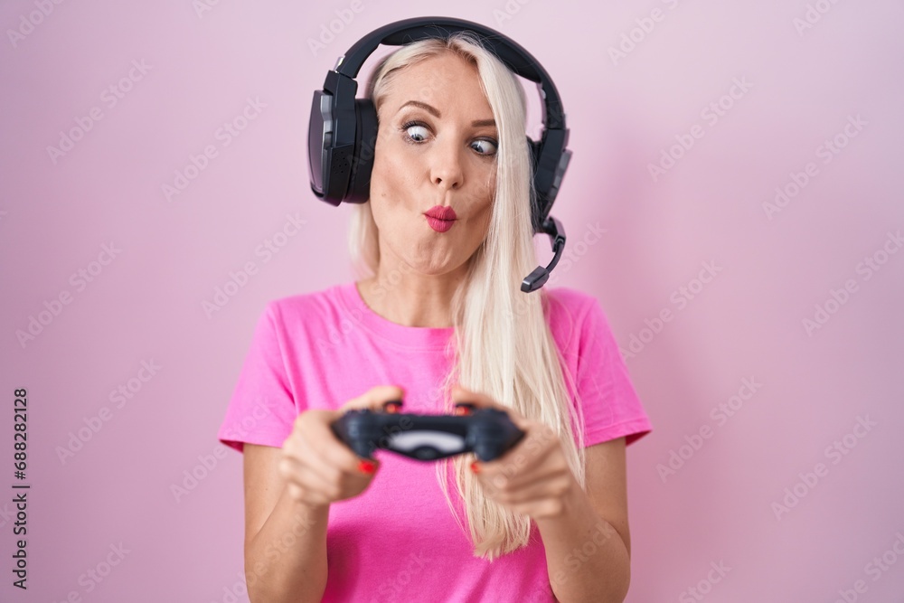 Canvas Prints caucasian woman playing video game holding controller making fish face with mouth and squinting eyes