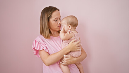 Relaxed mother hugging and holding her baby over a cool, lovely pink isolated background,...