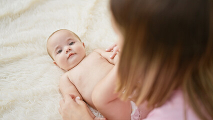 Mother and daughter's indoor bonding, playing together on the bed in the comfort of their family...