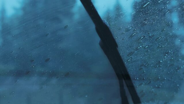 Vehicle wiper blades cleaning the windshield during heavy rainstorm while driving