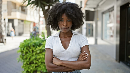 African american woman standing with serious expression and arms crossed gesture at street