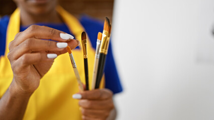 African american woman artist holding paintbrushes at art studio