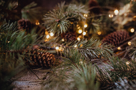 Christmas dark academia vintage winter wooden table with fir branches, pine cones, black candles and twinkle lights covered in fake snow