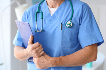 Mature doctor with clipboard in medical office, closeup