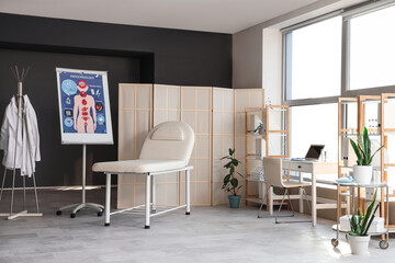 Interior of medical office with workplace, couch and folding screen