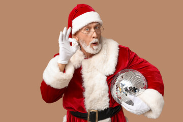 Santa Claus in glasses with disco ball trying to hear something on brown background