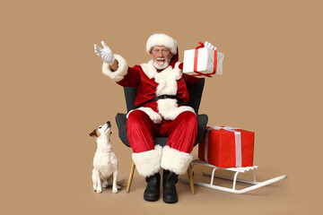 Santa Claus with cute Jack Russell Terrier dog and Christmas gift boxes on brown background