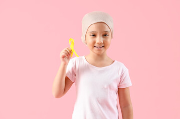 Little Asian girl after chemotherapy with ribbon on pink background. Childhood cancer awareness...