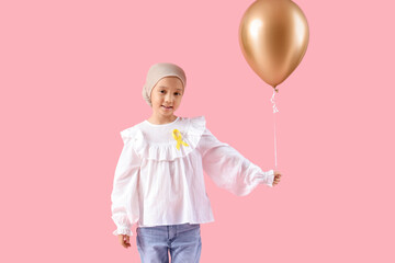 Little Asian girl after chemotherapy with ribbon and balloon on pink background. Childhood cancer awareness concept