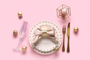 Beautiful table setting with Christmas balls and candle on pink background