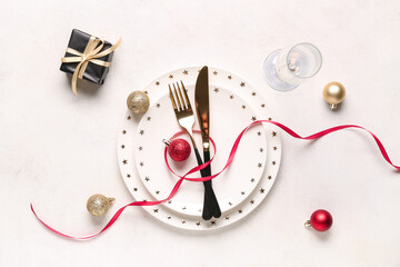 Beautiful table setting with Christmas balls and gift box on white background