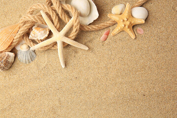 Fototapeta na wymiar Beautiful sea stars, shells and rope on sand, flat lay. Space for text