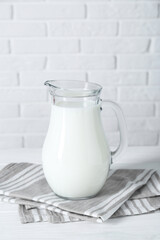 Jug of fresh milk on white wooden table