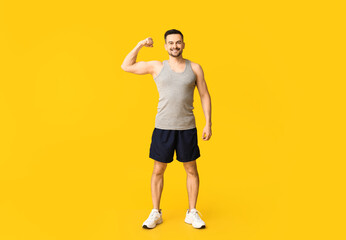 Fototapeta na wymiar Handsome sporty young man showing muscles on yellow background. Weight loss concept