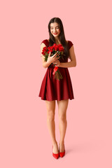 Happy young woman with kiss marks on her face and bouquet of roses on pink background