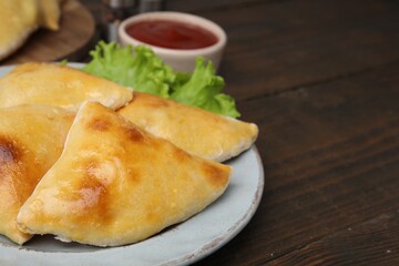 Delicious samosas and lettuce on wooden table, closeup. Space for text