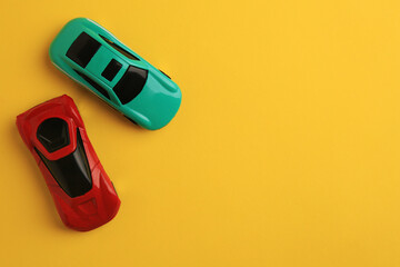 Bright cars on yellow background, flat lay with space for text. Children`s toys