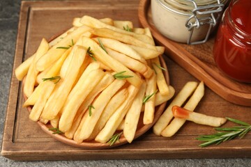 Delicious French fries served with sauces on grey textured table, closeup