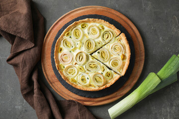 Tasty leek pie and fresh stalk on dark textured table, flat lay